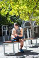 Handsome athlete tying shoelaces on a bench