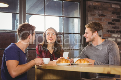 Friends talking and enjoying coffee and croissants