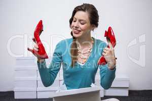 Happy brunette holding up red shoes