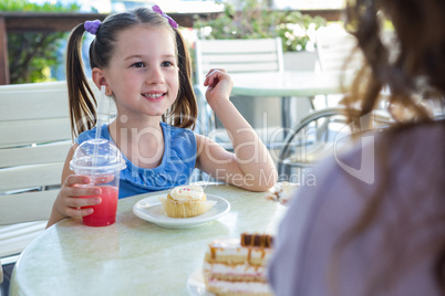 Mother and daughter enjoying cakes at cafe terrace