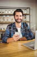 Young student enjoying a coffee and using his smartphone