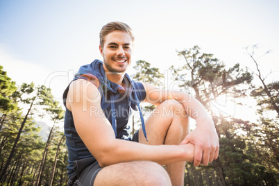 Young happy jogger sitting on rock and looking at camera