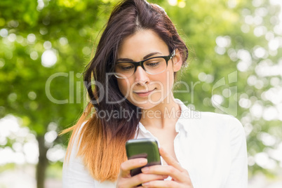 Beautiful brunette sending text in the park