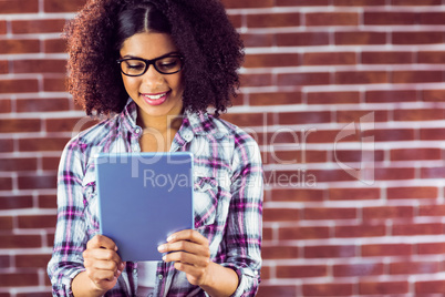 Attractive hipster smiling and looking at tablet