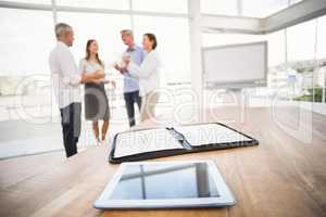 Tablet and planner in front of talking business people