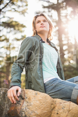 Young happy jogger sitting on rock and looking away