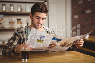 Hipster having coffee and reading newspaper