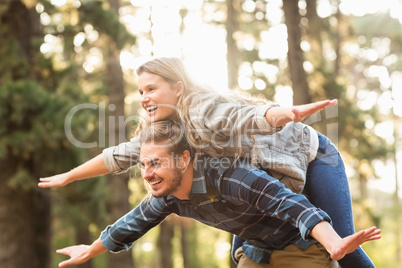 Smiling handsome man giving piggy back to his girlfriend