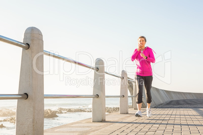 Smiling sporty woman jogging at promenade