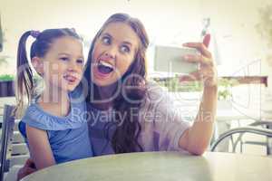 Mother and daughter taking selfie at cafe terrace