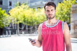 Handsome athlete sending a text