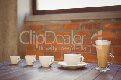 Several hot beverages in a row on wooden table