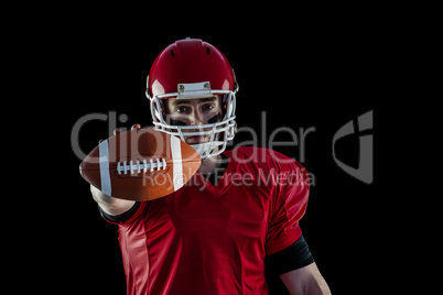 Portrait of american football player showing football to camera