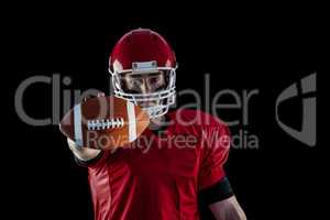 Portrait of american football player showing football to camera