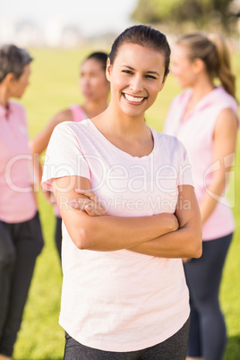 Smiling brunette wearing pink for breast cancer in front of frie