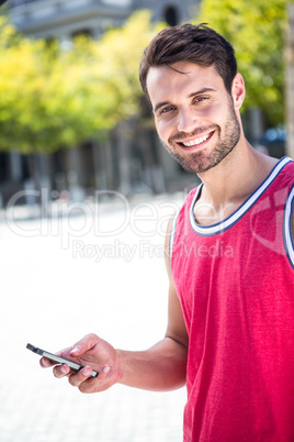 Smiling handsome athlete sending a text