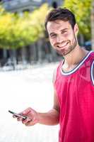 Smiling handsome athlete sending a text