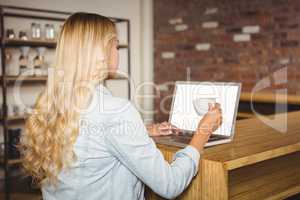 Rear view of blonde having coffee and using laptop