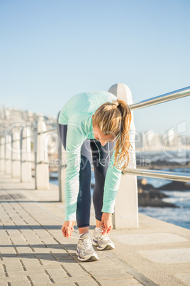 Fit blonde tying her shoelace and listening to music