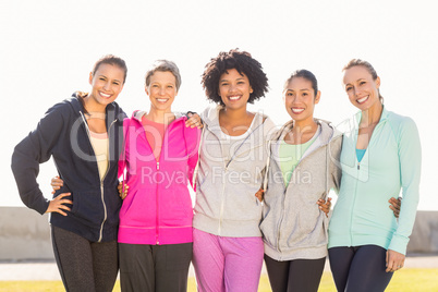 Smiling sporty women with arms around each other