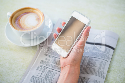 Woman having cappuccino using her phone