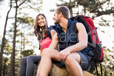 Young happy joggers sitting on rock and looking away