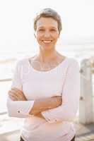 Smiling sporty woman with arms crossed at promenade