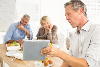 Casual business people looking at tablet while lunch