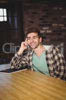 Smiling hipster phoning with smartphone