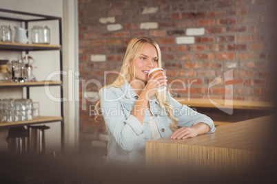 Smiling blonde drinking out of take-away cup