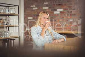 Smiling blonde drinking out of take-away cup