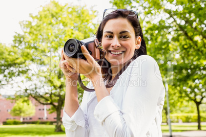 Beautiful brunette taking photo in the park