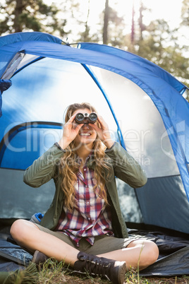 Smiling blonde camper looking through binoculars