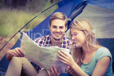 Young pretty hiker couple sitting in a tent looking at map