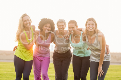 Smiling sporty women with arms around each other