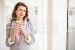 Smiling casual businesswoman holding take-away cup