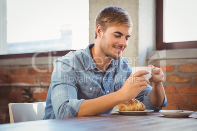 Handsome man enjoying coffee and croissant