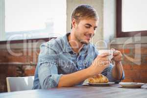 Handsome man enjoying coffee and croissant