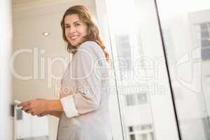 Smiling casual businesswoman holding smartphone