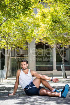 Handsome athlete stretching his leg on the ground