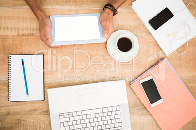 Hands holding tablet next to several devices