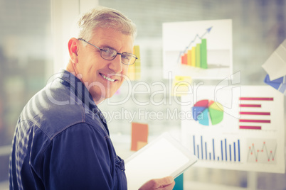 Smiling businessman holding a digital tablet