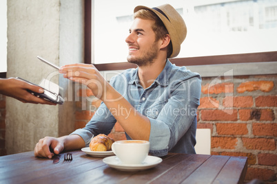 Handsome hipster paying with smartphone