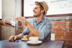 Handsome hipster paying with smartphone