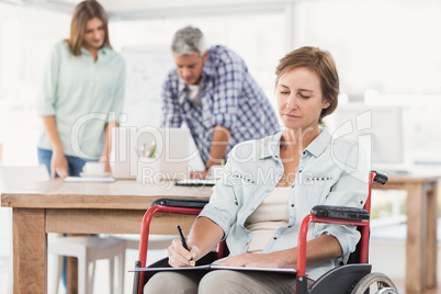 Casual businesswoman in wheelchair taking notes
