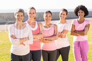 Smiling women wearing pink for breast cancer with arms crossed