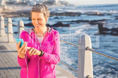 Smiling sporty woman enjoying music and holding phone