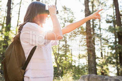 Smiling brunette hiker looking through binoculars