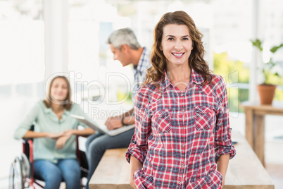 Casual female artist with colleagues in background at office