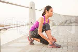 Fit woman tying shoelace at promenade